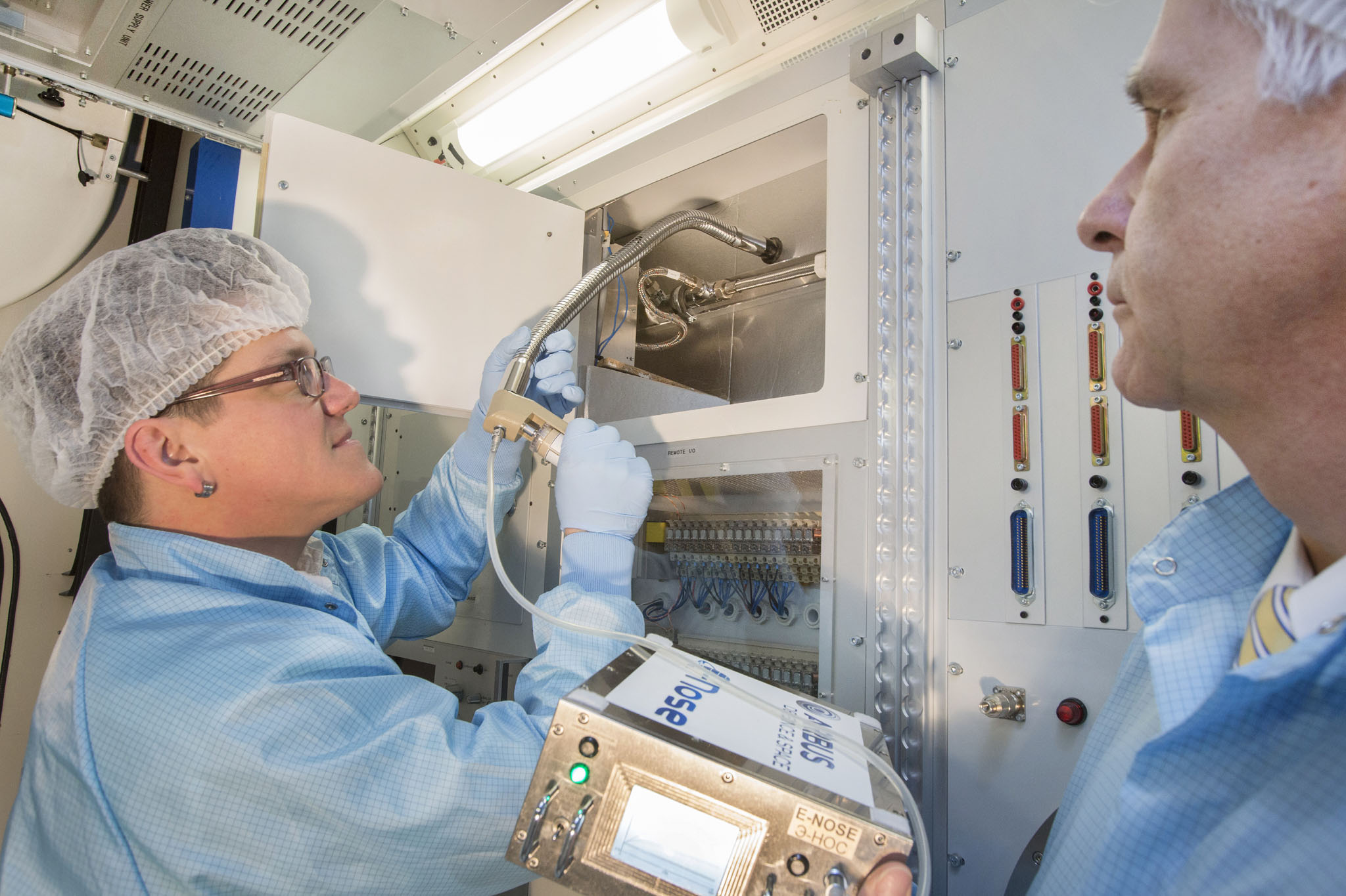 The new, trunk-like instrument of the ‘E-nose’ can detect micro-bacterial contamination in every corner of the Space Station. Viktor Fetter (left) and Thomas Hummel from Airbus Defence and Space take samples in an ISS ground module. © Airbus DS GmbH