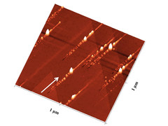 Nanostructures on a crystal after ion bombardment: Trenches with nanohillocks on either side are created. At the impact site, a particularly large nanohillock is formed.